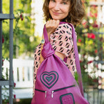 pink leather handbag on a woman's shoulder in a roses garden
