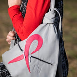 grey leather design backpack with a pink ribbon on a shoulder of a woman