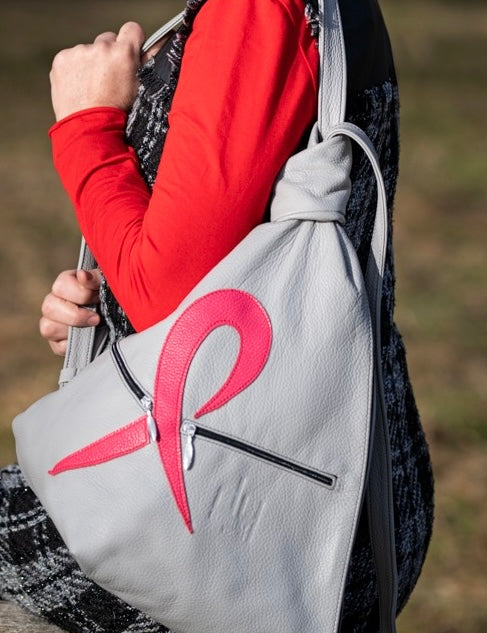 grey leather design backpack with a pink ribbon on a shoulder of a woman