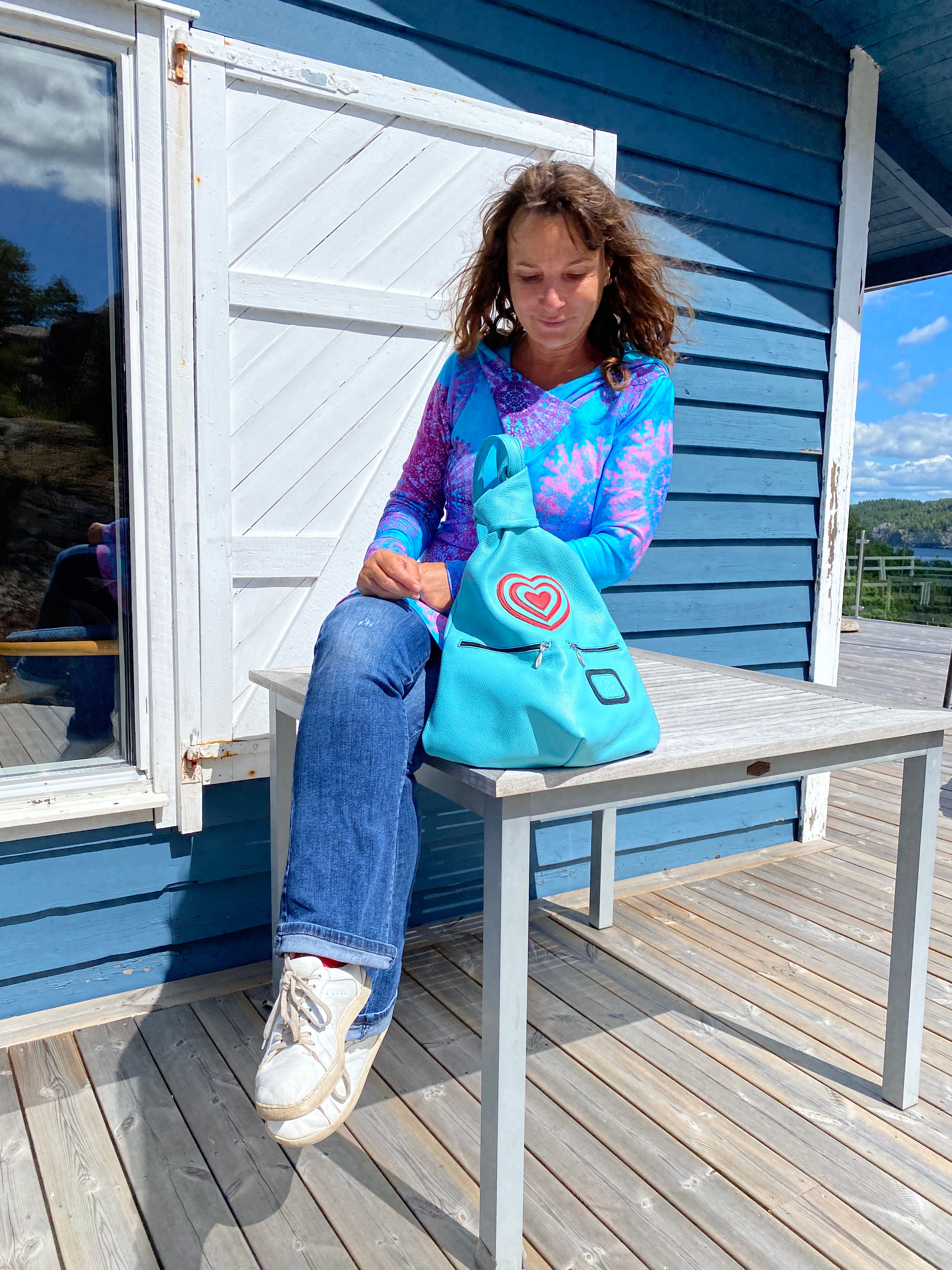 Blue leather artisan backpack with hearts with a woman on the table in Sweden