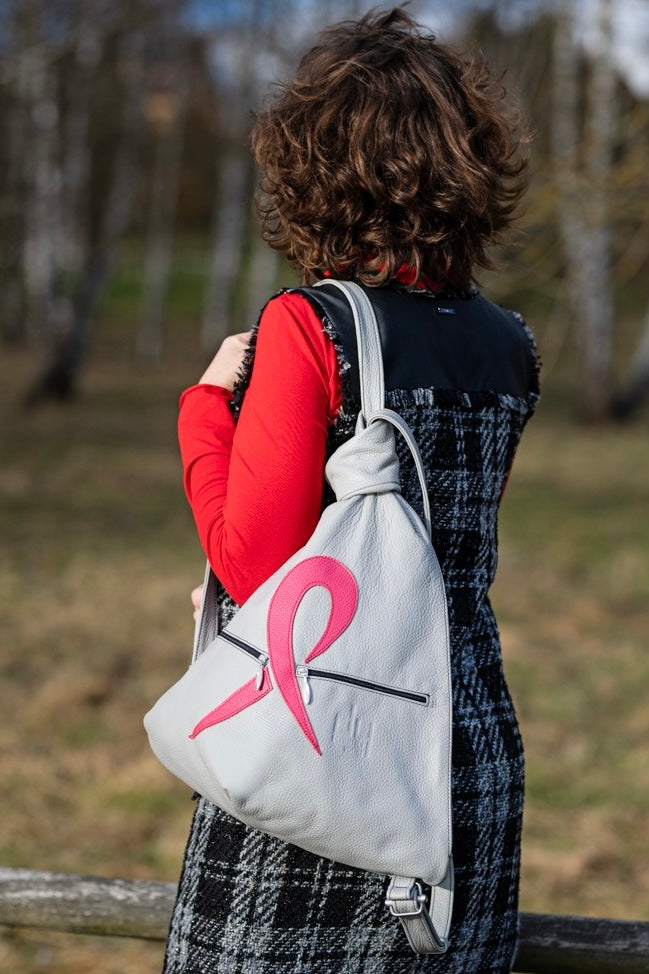 grey leather artisan backpack with pink ribbon on a shoudler of a woman
