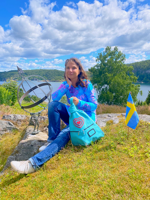 Blue Romantic Handmade Leather Backpack with Heart Details with woman on a rock in Sweden